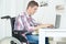 Student in wheelchair typing on laptop in library