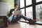 Student working with laptop sits on the floor near the window