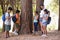 Students examining tree trunk with teacher in forest