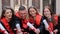 Students graduates in academic gowns with diplomas in hand posing for camera.