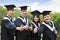 students in graduation gowns showing diplomas with thumbs