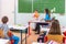 Students read a woman teacher at the blackboard