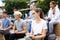 Students record lecture while sitting on a stone street parapet