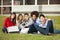 Students Sitting On Grass At College Campus