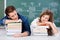 Students Sleeping On Stack Of Books Against Chalkboard