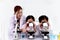 Students and teacher in lab coat have fun together, two little children students look through microscope and learn science