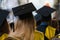 Students wearing gowns and hats sitting indoors, waiting to receive diplomas, graduation day in university, college commencement