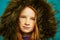 Studio close-up portrait of cute redheaded child girl with freckles hid in large hood jacket.