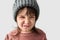 Studio closeup portrait of cute unhappy little girl with grumpy emotion in the winter warm gray hat, wearing sweater isolated on a