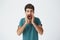 Studio closeup shot of stylish spanish young hipster in blue t shirt, with nervous expression, screaming and cheering