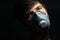 Studio dramatic dark portrait. Close-up of young man wearing protective flu mask on background of black color.