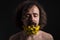 Studio dramatic portrait of a young guy of thirty years old, with his eyes closed. yellow flowers are woven into curly