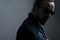 Studio dramatic shadow portrait of a young bearded guy with glasses, in a denim jacket, on a gray background. Dramatic light. dark