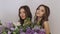 Studio fashion portrait photo of two twins women with a bouquet of spring flowers