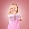 Studio, giving present portrait of a child for birthday, holiday or happy celebration. Excited girl kid on a pink