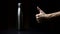 Studio image, close-up of male hand showing thumbs up about reusable, steel thermo water bottle on table, isolated on black