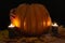 The studio photo of burning candles. Human hand on Pumpkin with spider and spiderweb on a black background. Halloween conceptual