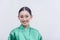 A studio picture of a lovely young Southeast Asian woman wearing a green silk satin bathrobe smiling for the camera. Plain white