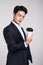 Studio portrait of an Asian business man posing with a disposable coffee cup