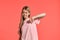 Studio portrait of a beautiful girl blonde teenager in a rosy t-shirt posing on pink background.