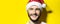 Studio portrait of close male face, smiling man wearing Christmas hat on yellow background with copy space.