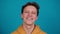 Studio portrait of confident smiling young man laughing against blue background - shot in slow motion