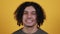 Studio portrait of confident smiling young man laughing against yellow background - shot in slow motion