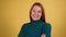 Studio portrait of confident smiling young woman laughing against yellow background