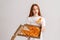 Studio portrait of dissatisfied young woman eating bad quality pizza holding box in hands looking away standing on white