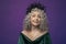 Studio portrait of an elderly woman 60-65 years old in a beautiful dress with a crown on her head on a colored background. Concept