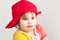 Studio portrait of funny confused girl in red baseball cap