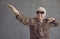 Studio portrait of funny dancing rich senior man in leopard shirt and cool glasses