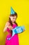 Studio portrait of a little girl wearing a party hat on her birthday. Cute girl open her birthday gift box