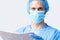 Studio Portrait Of Male Surgeon Wearing Gown And Mask Holding Medical Print Out