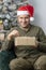 Studio portrait of a man of oriental appearance 30-35 years old unpacks a gift box on the background of a Christmas tree