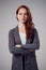 Studio Portrait Of Serious Young Businesswoman With Folded Arms Against Plain Background