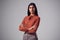 Studio Portrait Of Serious Young Businesswoman With Folded Arms Against Plain Background