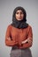 Studio Portrait Of Serious Young Businesswoman With Folded Arms Wearing Headscarf Against Plain Background