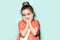 Studio portrait of shy little child girl, holding palms on cheeks. Background of aqua menthe color. Wearing coral shirt.