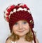 A studio portrait of a smiling little girl in a purple knitted cap