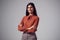 Studio Portrait Of Smiling Young Businesswoman With Folded Arms Against Plain Background