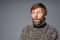 Studio portrait of surprised mature man in warm sweater looking to side