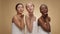 Studio portrait of three playful multiethnic ladies sending blow kisses to camera, posing wrapped in towels