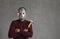 Studio portrait of an unknown man on a gray background who is dressed in a spooky maniac mask.