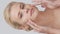 Studio portrait of young, beautiful and natural blond woman applying skin care cream. Vertical video. the concept of