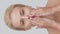 Studio portrait of young, beautiful and natural blond woman applying skin care cream. Vertical video. the concept of