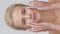 Studio portrait of young, beautiful and natural blond woman applying skin care cream. Vertical video. the concept of