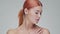 Studio portrait of young, beautiful and natural redhead woman applying skin care cream. Face lifting, cosmetics and make