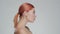 Studio portrait of young, beautiful and natural redhead woman applying skin care cream. Face lifting, cosmetics and make