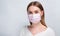 Studio portrait of young woman wearing a face mask, looking at camera, close up,  on gray background. Flu epidemic, dust